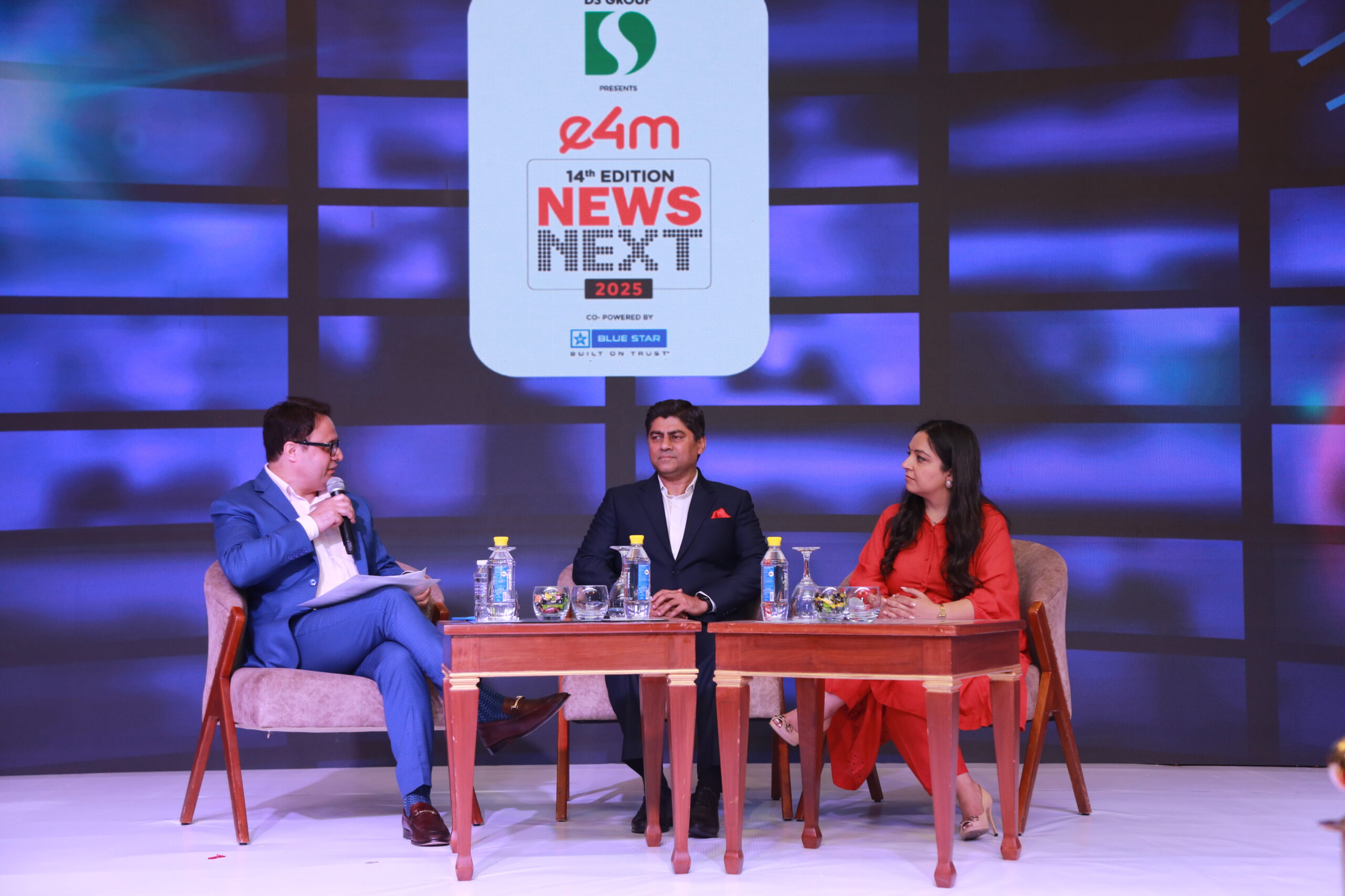 Ruhail Amin speaking into a handheld microphone while moderating onstage